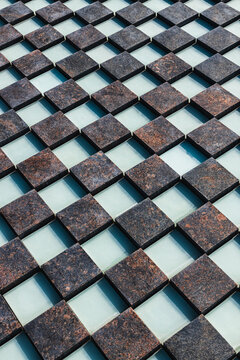 Repeating dark stone tiles arranged in a geometric diamond grid with turquoise gaps and varied natural textures, viewed from above as a patterned surface
