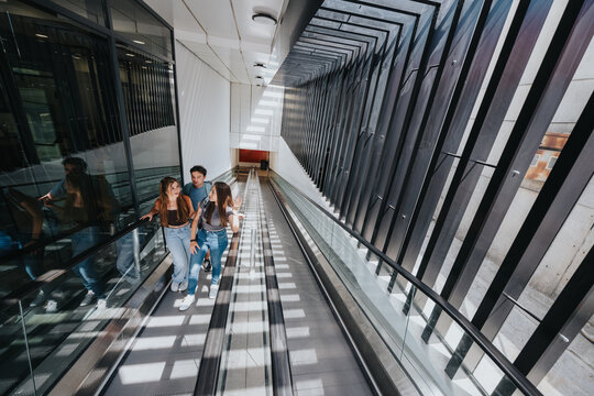 Students and friends ride an escalator with backpacks inside a university transit building, talking during their daily commute.