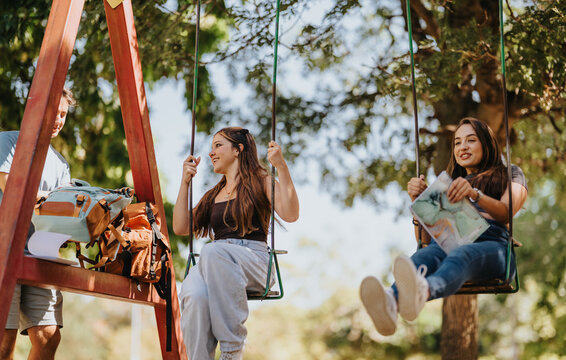 Students swing and relax at an outdoor playground, enjoying friendship, recreation and a casual campus break.