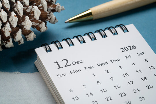 December 2026 - small spiral desktop calendar against art paper abstract, time and business concept