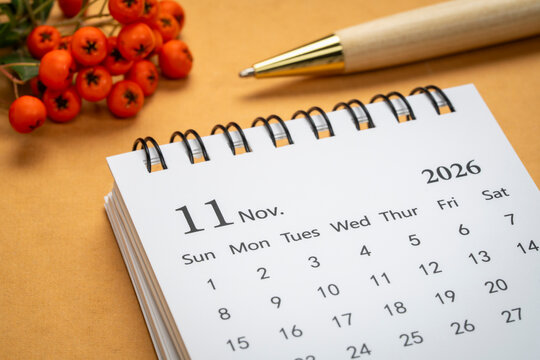 November 2026 - small spiral desktop calendar against art paper, time and business concept