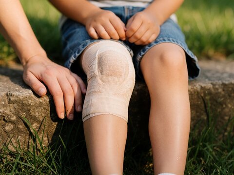 Child with injured knee wearing bandage