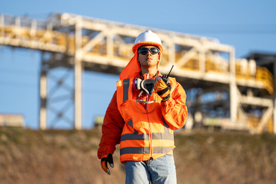 Mining worker holding a two-way radio with an industrial plant in the background in northern Chile