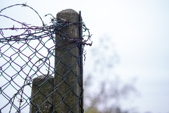 Wire fencing wrapped around a concrete post outdoors in winter