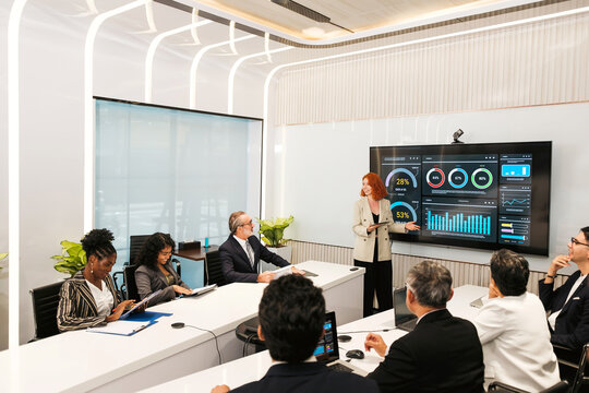 Businesswoman presents analytics to colleagues in a modern boardroom