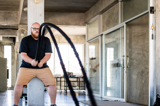 Man trains with battle ropes in an industrial gym