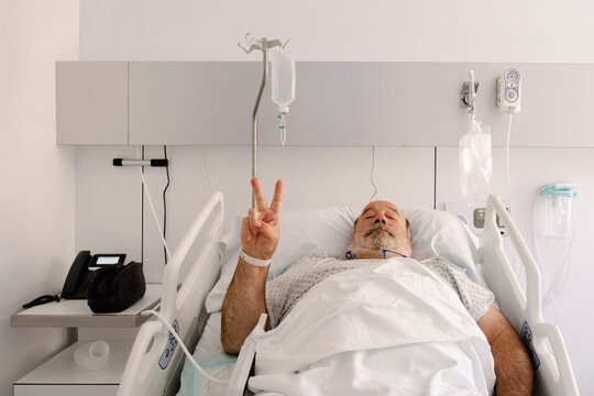 UGC Male hospital patient resting in bed and making peace sign