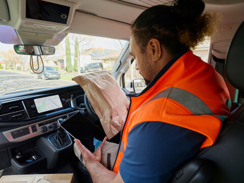 Worker Sits in Van Using iPad To Check Off Delivery Items