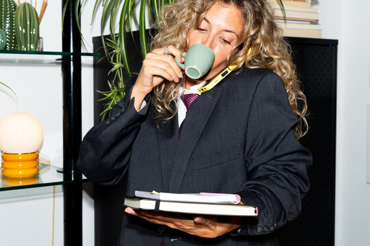 Businesswoman multitasking in office setting with phone and coffee