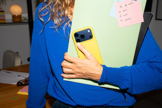 Person holding a folder and phone in a workspace
