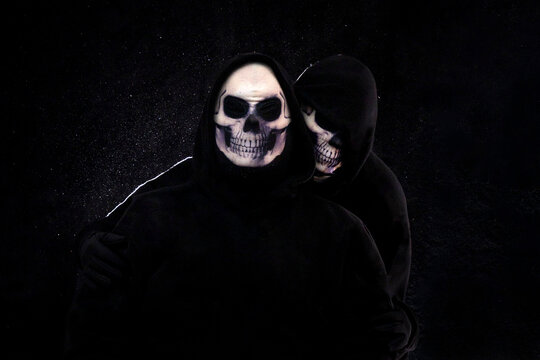 People wearing skull masks and black clothes against a black background.
