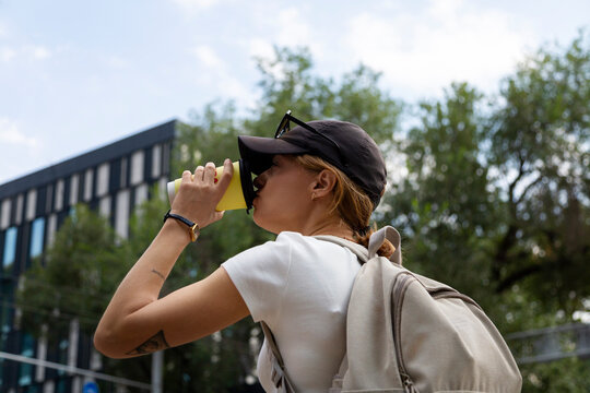 Woman drinking takeaway coffee outdoors with backpack