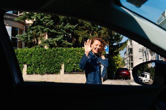 Woman Waving Goodbye from Car Window