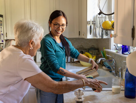 Senior companion Caregiver smile doing dishes kitchen