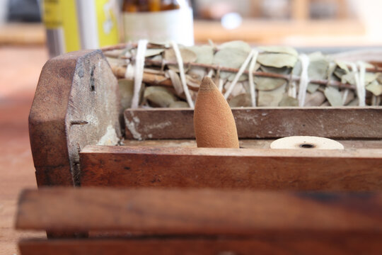 Incense cone in wooden tray with defocused Smudging kit. Close up. Unlit incense cone. Spiritual cleansing, aromatherapy and wellbeing concept. Selective focus.
