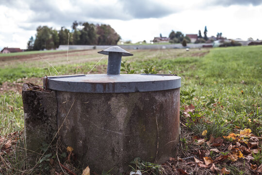 Agricultural groundwater access point or irrigation supply well. Low angle view with vent cap and defocused farmland. Lucerne, Switzerland. Selective focus.