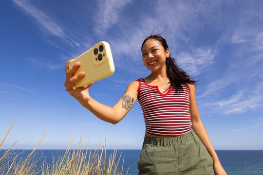 Asian Girl with Cell phone Summer Beach Ocean selfie