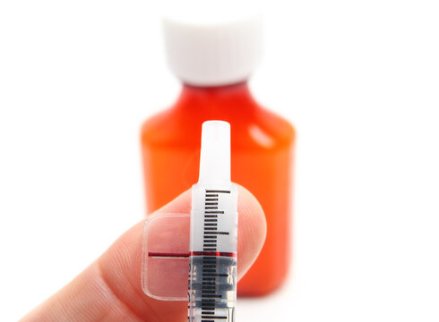 Dosing syringe with oral steroid medication bottle. Close up. Liquid anti-inflammatory for pets or children, dispensed by owner or parent. Dosage line visible. Selective focus.