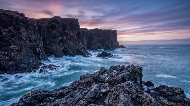 Ocean waves break against rocky cliffs at sunset along a rugged coastline