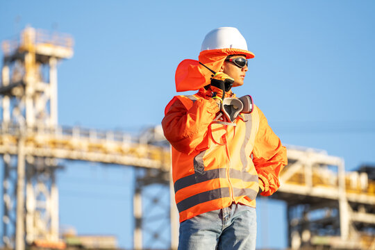 Mining worker using a two-way radio near an industrial plant in northern Chile