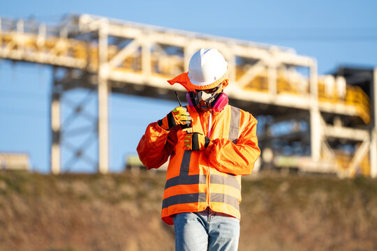 Mining worker putting a walkie-talkie into his jacket pocket near an industrial plant in northern Chile