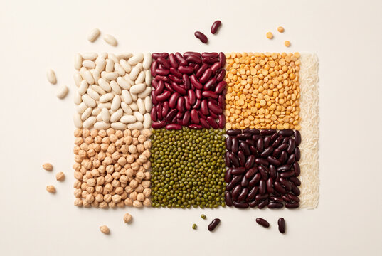 Top view of assorted legumes and rice arranged in neat blocks on beige background
