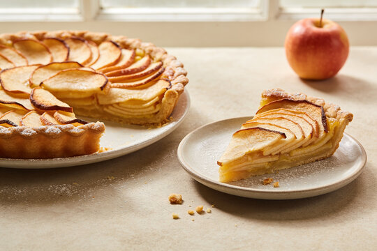 Apple tart and a plated slice on a softly lit kitchen table