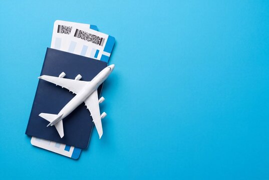 Top view of airplane model, passport and boarding passes on blue background with copy space