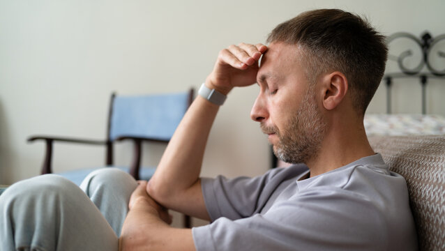 Mental Exhaustion and Burnout from Stress, Tired Man at Home Holding Forehead with Closed Eyes.