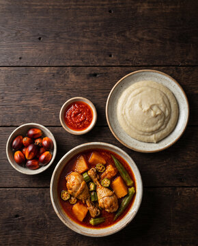 Angolan muamba de galinha chicken in palm oil with okra, pumpkin and funge on dark wood, top view with copy space, vertical
