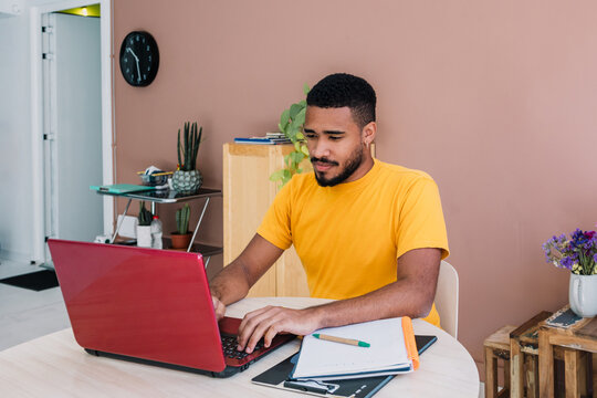 young latino man using laptop in a workplace in Latin America, freelance hispanic male working at creative office