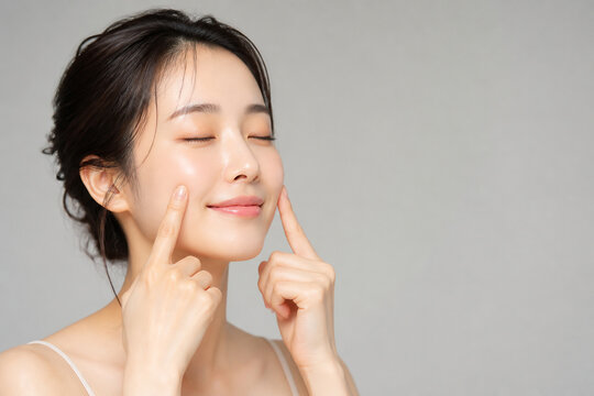 目を閉じて両頬に指を添える女性