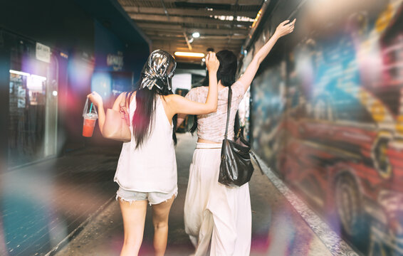 Rear view of two young asian woman hanging out with friends at Khao san walking street hipster style