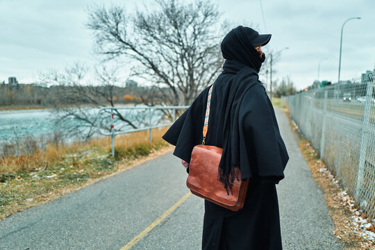 Woman Standing on a Riverside Path Looking Toward the Water