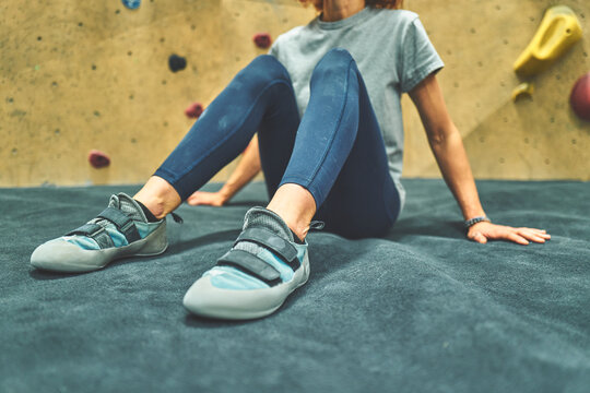 Woman Sitting on a Crash Mat Wearing Teal Climbing Shoes