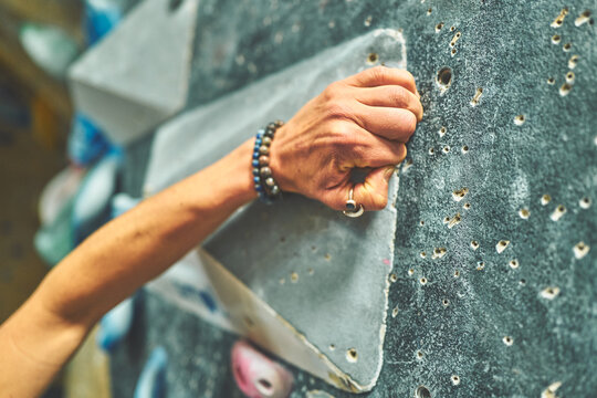 Woman's Hand Crimping the Edge of a Grey Bouldering Volume