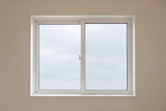 Interior view of a white double glazed sliding window with a cloudy sky outside