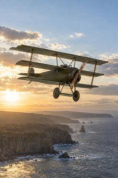 Vintage triplane flypast over the coast against the low sun