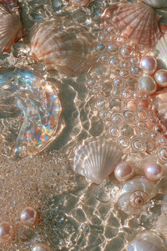 Perlmuttfarbene Muscheln und Seifenblasen im Wasser in Rosa und Gold