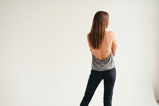 Woman seen from behind in a backless grey top on a white studio