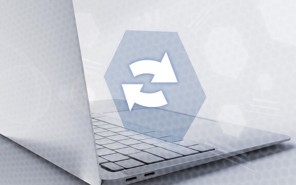 Una representaci&oacute;n digital de una aplicaci&oacute;n inform&aacute;tica con un icono de sincronizaci&oacute;n sobre un ordenador port&aacute;til plateado en un entorno tecnol&oacute;gico moderno.