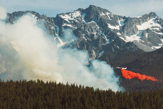 Firefighting airplane dropping fire retardant on forest wildfire