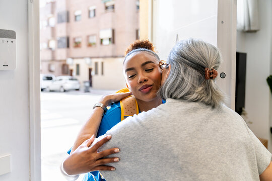 Latina home health nurse embracing an elderly woman during a home visit, sharing a warm greeting at the doorway