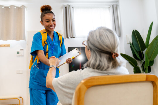 Latina home health nurse greeting an elderly woman and reviewing care notes during a compassionate in home visit