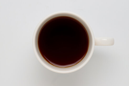 白背景に置いたコーヒー入りの白いコーヒーカップを真俯瞰で撮影