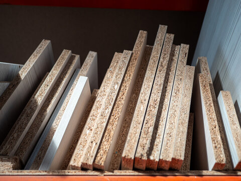 Particleboard offcuts and leftover laminated chipboard panels stored upright on a workshop shelf. Woodworking waste, furniture production scraps and reusable materials in carpentry storage.