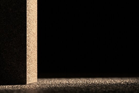 Textured cork wall corner meeting horizontal ground surface, brown organic material background