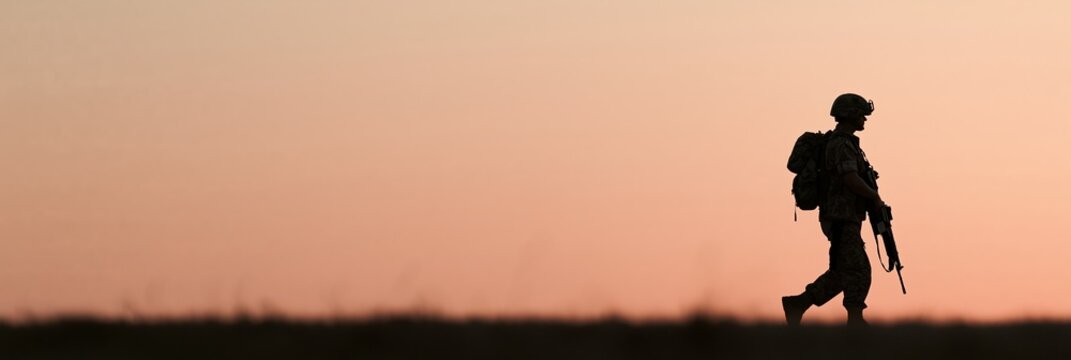 Soldier silhouette walking through open field at dawn, representing duty and military service