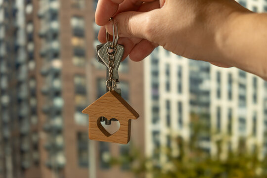 Buying or renting real estate, moving to apartment. Hand holding keys outside.