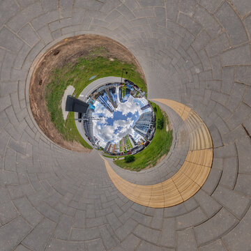 creative tiny planet photo of a rural landscape with dirt road, green fields, and cloudy sky forming a circular world.